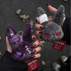 A hand holds a dark purple gothic bunny plush keychain with a white bandage design against a gray background.