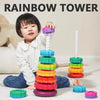 A toddler is playing with a colorful rainbow stacking tower made of rings and a spire.
