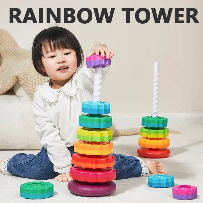 A toddler is playing with a colorful rainbow stacking tower made of rings and a spire.