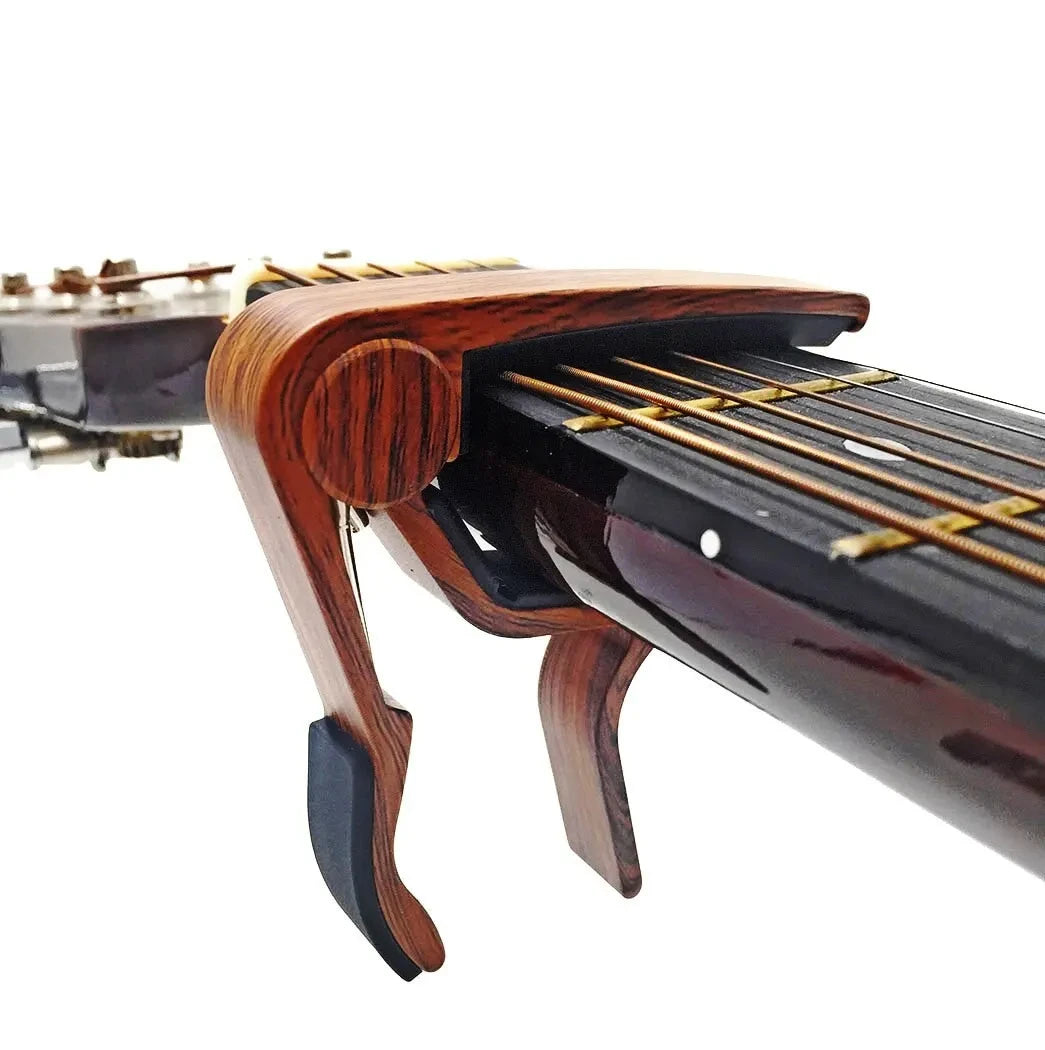 Close-up of a rosewood guitar capo with five picks for acoustic and electric guitars