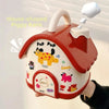 A red house-shaped piggy bank with a yellow dog design is held by a hand.