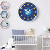 A round blue and yellow analog teaching clock hangs on a white wall above a crib and decorative hexagonal frames.
