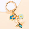 Gold-toned keychain featuring an enamel bee and a daisy flower design.