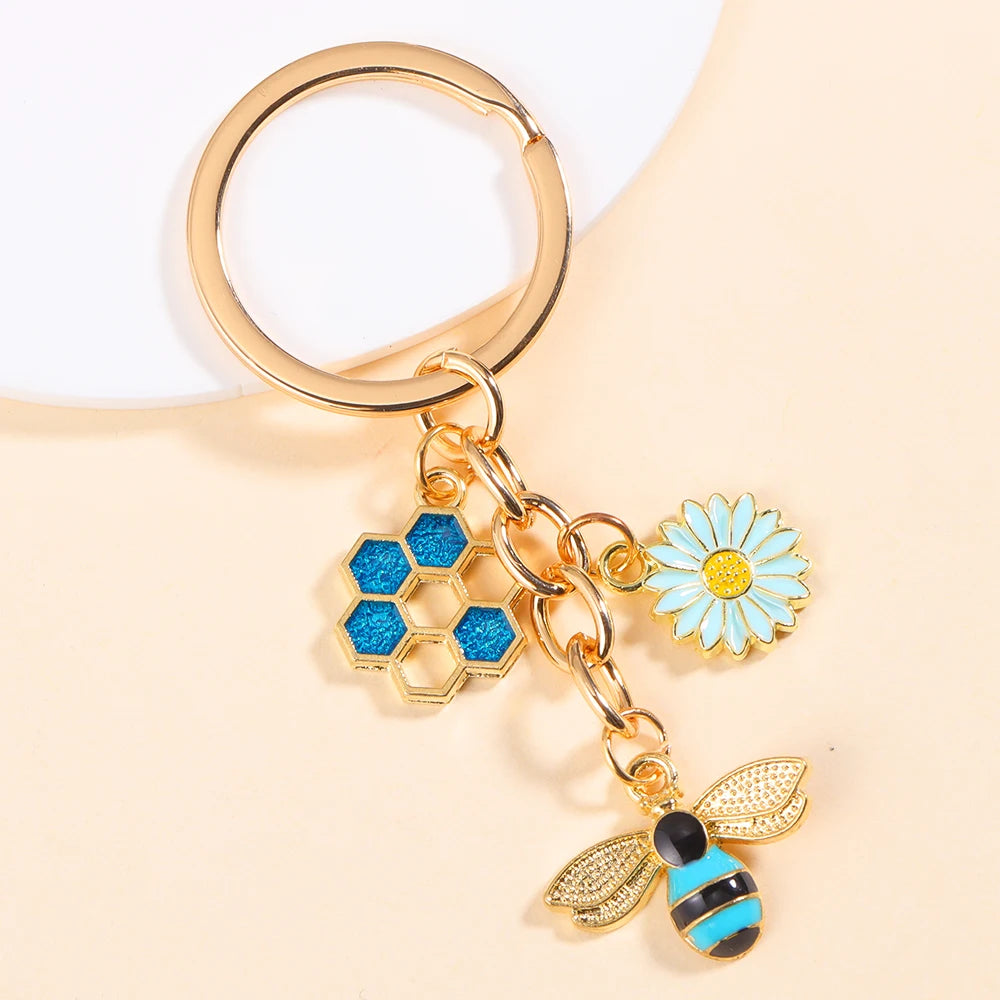 Gold-toned keychain featuring an enamel bee and a daisy flower design.