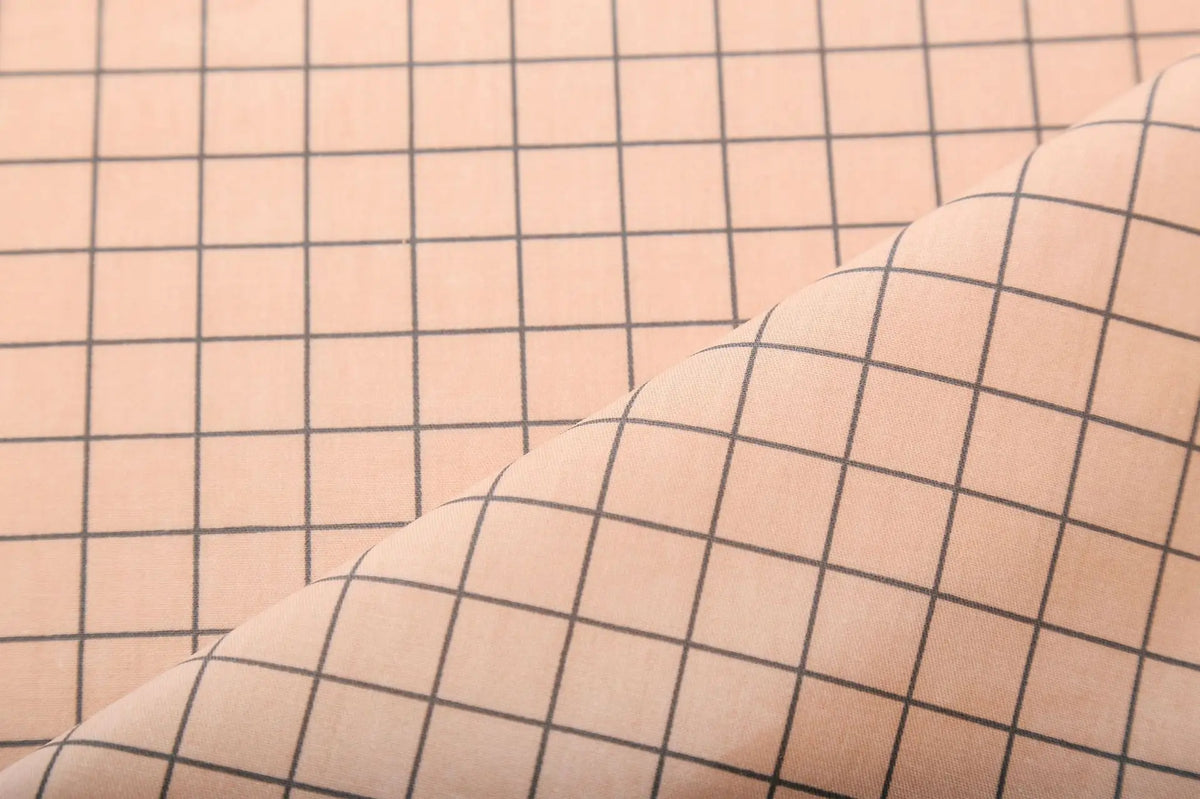 Close-up of beige grid print fabric with diagonal stitching detail.