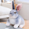 A cute gray and white rabbit plush toy sitting on a wooden surface.