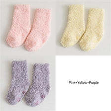 Three pairs of baby anti-slip fleece socks in pink, yellow, and purple.
