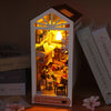 A DIY book nook kit featuring a wooden bookshelf insert with warm LED lighting and decorative elements.