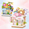 A mini city shop building block set featuring a fruit stand and a candy shop with pink and yellow elements.