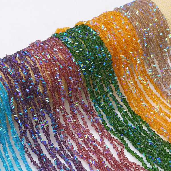 Gros plan de perles triangulaires en cristal multicolores, dans des tons de violet, bleu, vert et orange, enfilées.