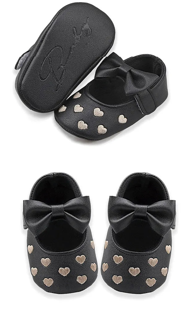 Pair of black baby girl bow-knot first walker shoes with gold heart accents and a soft anti-slip sole