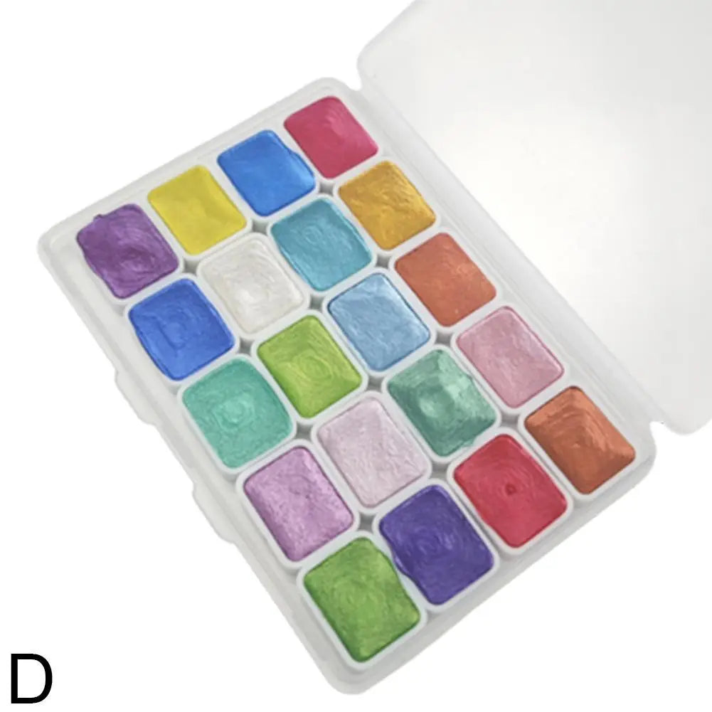 A square white tin holds twenty colorful pearl watercolor paint pans arranged in a grid.
