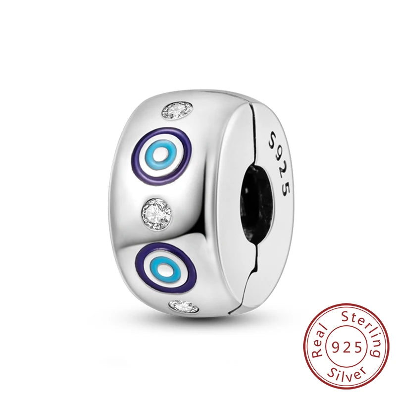 A silver die with three colored eye designs and the marking 925 Sterling Silver.