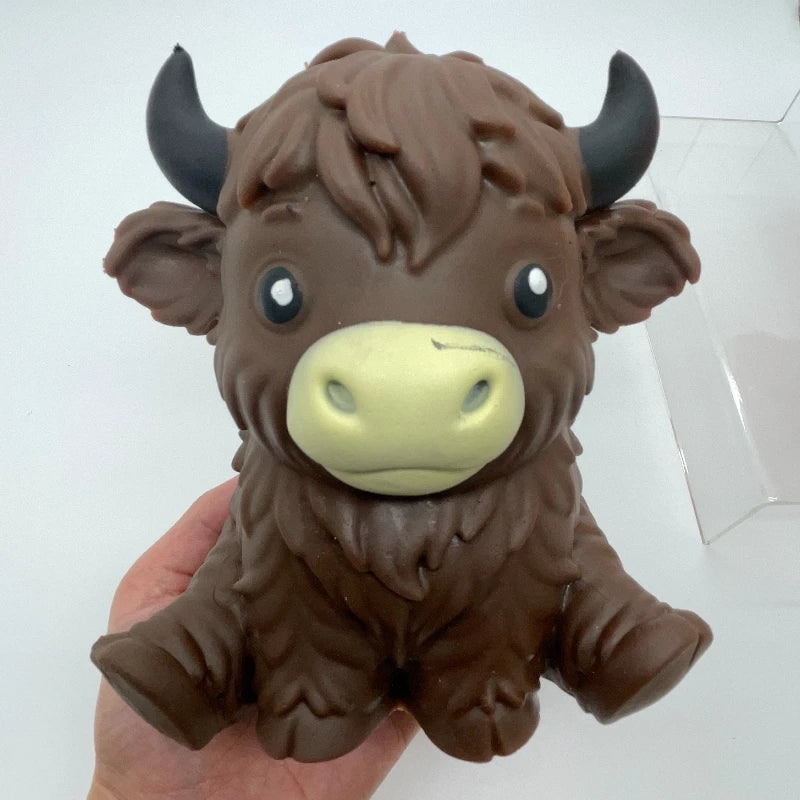 A brown squishy stress ball shaped like a Highland cow with horns and large eyes.