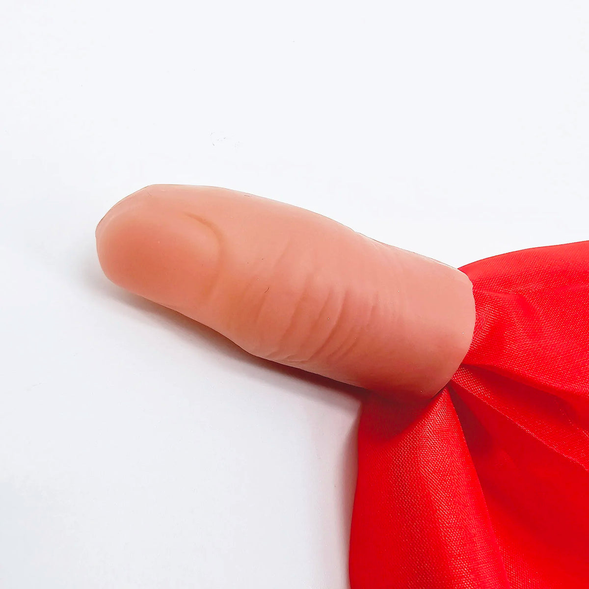 Gros plan d'un doigt portant un tissu de soie rouge, utilisé comme accessoire pour un tour de magie.