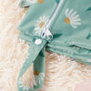 A teal reusable waterproof baby wet bag with a zipper and fabric strap lying on a fluffy white surface.