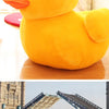 A bright yellow plush toy shaped like a duck resting on a wooden surface.