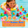 A young girl is smiling while holding a yellow inflatable rubber duck in clear blue water surrounded by various colored rubbe
