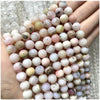 A hand holds a string of natural stone beads including amethyst, garnet, and labradorite for jewelry making.