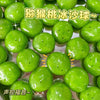 A close-up shot of numerous bright green watermelon kiwi squishy stress balls resting on a reflective surface.