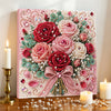 A pink floral painting kit featuring roses and greenery with pearl accents displayed on a wooden surface.