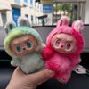 A hand holds a pink Labubu The Monsters Big Into Energy plush doll with pink fur and large eyes.