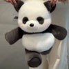 A white and black panda stuffed animal is being held up against a light background.