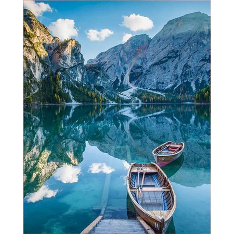 A wooden sailboat rests on clear turquoise water with mountains reflected in the calm surface.