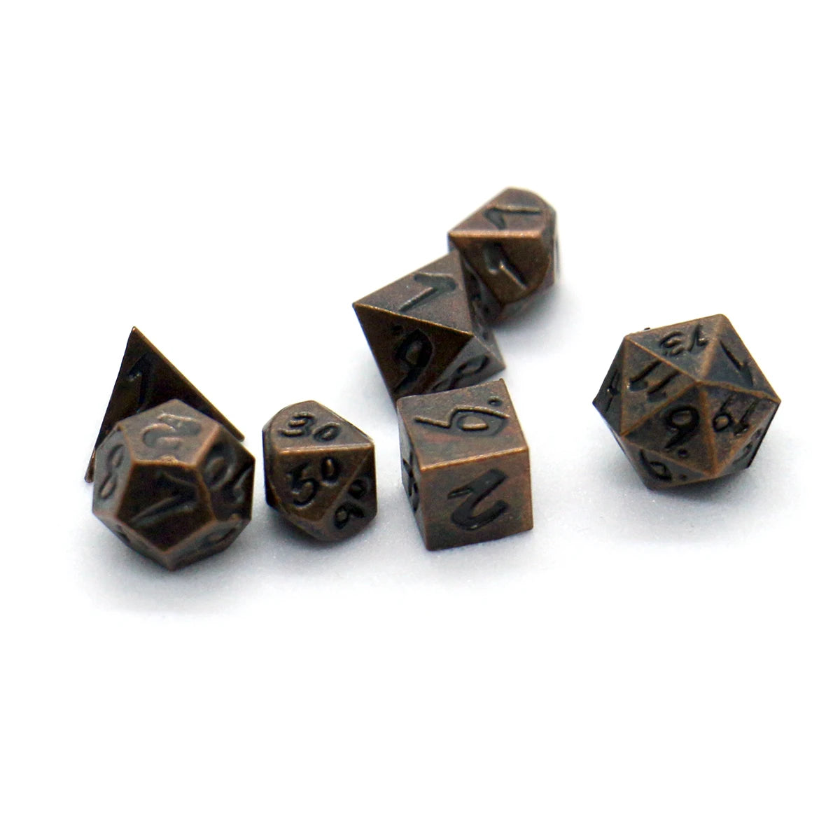 A collection of seven antique metal polyhedral dice, including d6s and d10s, scattered on a white background.