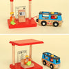 A wooden train track accessory set featuring a red and pink station and a blue and yellow wooden train.