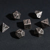 A collection of small, silver-colored metal dice scattered on a dark surface.
