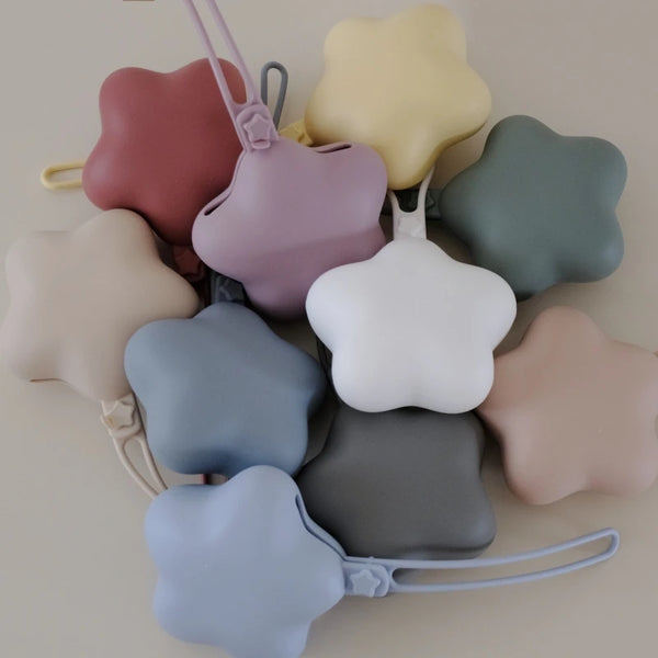 A collection of soft, pastel-colored portable pacifiers and teethers with attached straps.