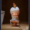A white candle-shaped collectible figurine with a glowing flame sits on a terracotta holder.