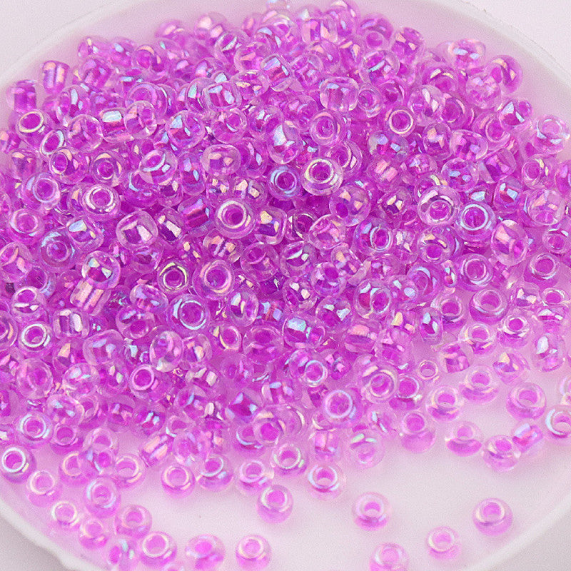 A pile of small, translucent purple glass rice beads for DIY jewelry and crafting.