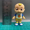 A playful cartoon PVC figurine of a child with a watermelon school bus design, standing next to a ruler.