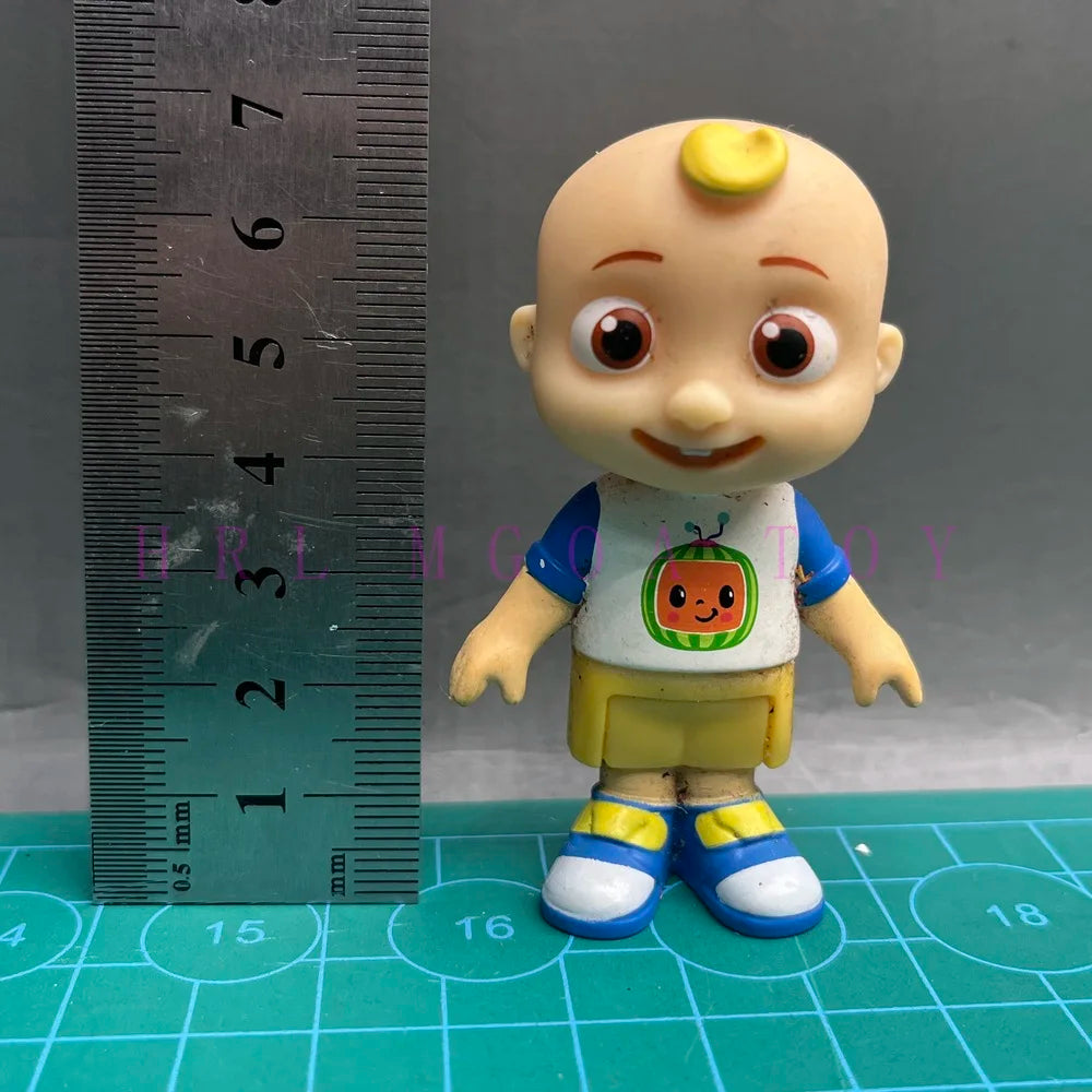 A playful cartoon PVC figurine of a child with a watermelon school bus design, standing next to a ruler.