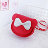 A red kids' hard shell crossbody bag with white bow and mouse ears resting on a white mesh basket.