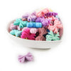A bowl filled with various colored silicone bow tie beads for jewelry making and craft projects.