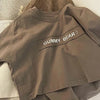 A plain taupe short-sleeve t-shirt with the text GUMMY BEAR printed on the chest.