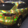 A yellow car with a holographic chrome vinyl wrap finish parked indoors.