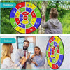 Two adults play an interactive sticky ball dart game indoors, aiming at a target board.