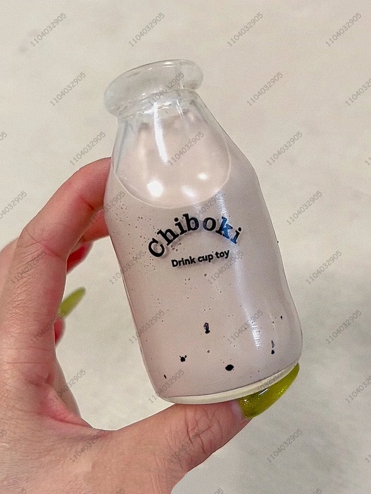 A hand holds a clear plastic bottle filled with a pink liquid labeled Chiboki, which is a drink cup toy.