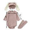 A mauve baby romper set featuring a rabbit hat and matching socks.