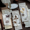 A collection of vintage scrapbooking paper, dried botanicals, and decorative elements arranged on a wooden surface.