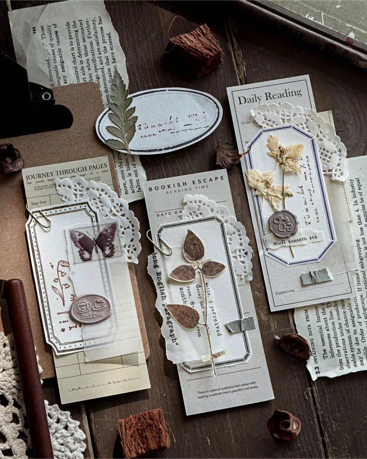 A collection of vintage scrapbooking paper, dried botanicals, and decorative elements arranged on a wooden surface.
