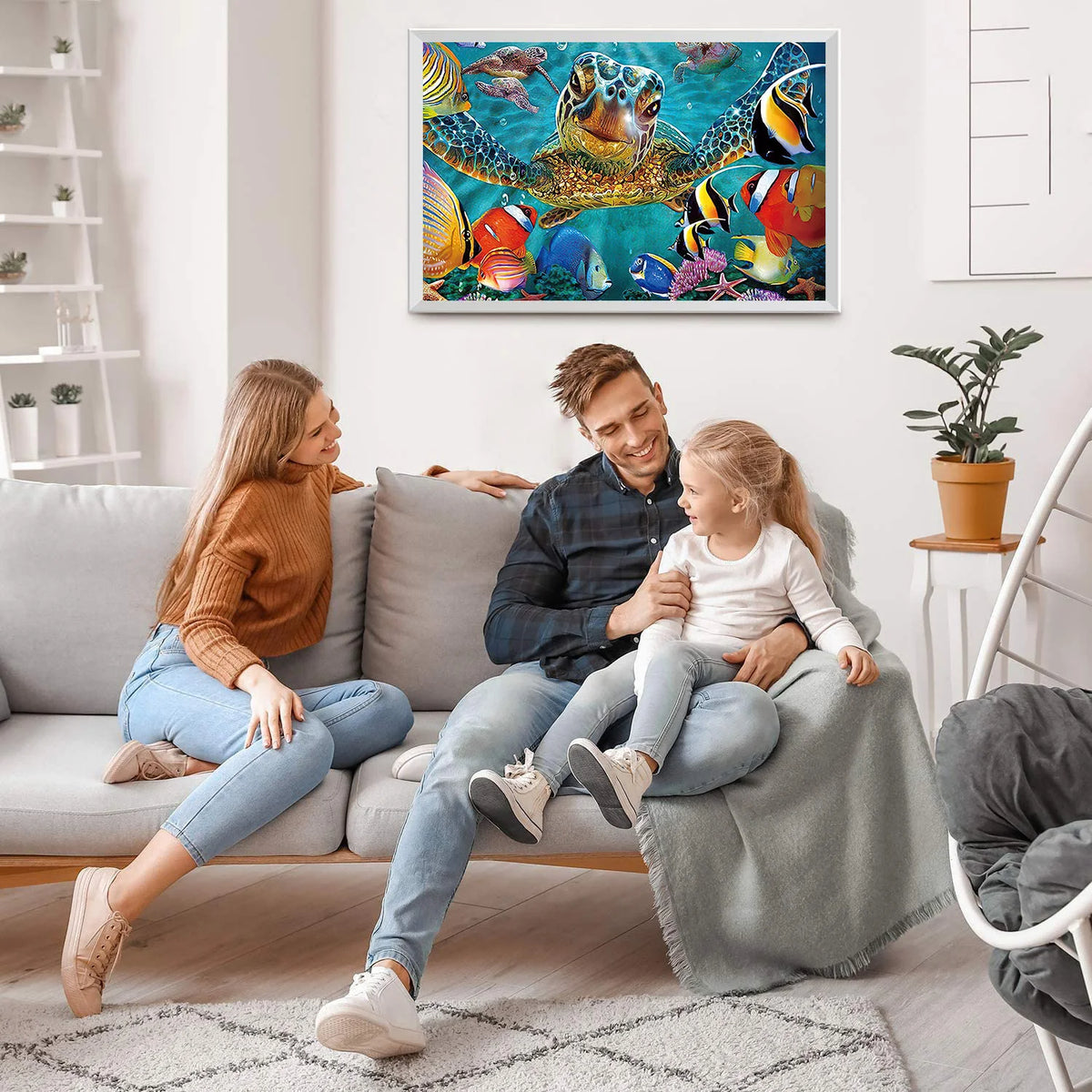 A family of three is sitting on a sofa in a living room, looking at a framed jigsaw puzzle of an ocean giant turtle.
