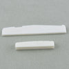 Two white guitar nut and bridge saddle components lying on a gray surface