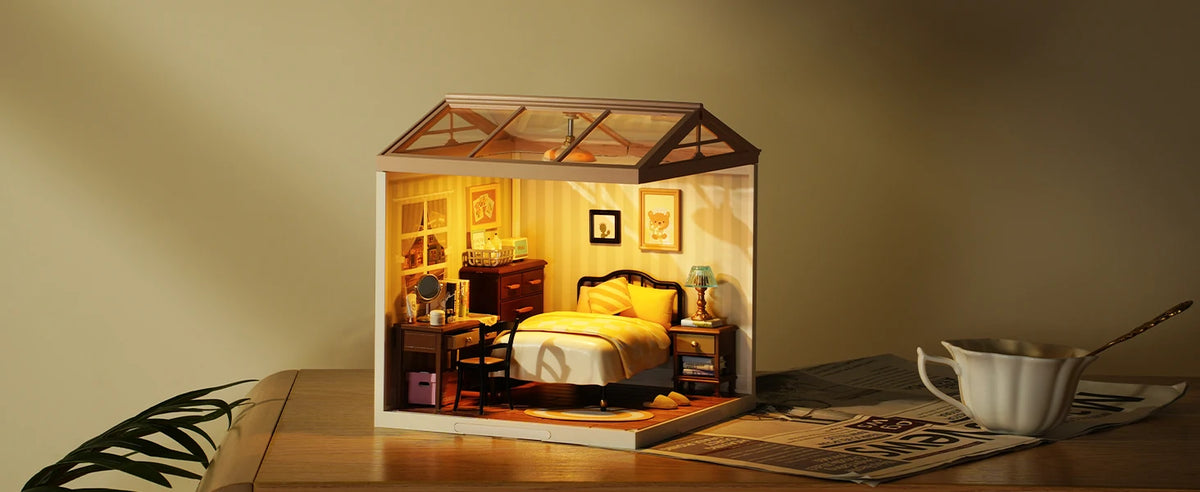 A DIY miniature dollhouse kit of a sweet dream bedroom with LED lighting displayed on a wooden surface.