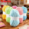 A collection of colorful soft chunky yarn skeins in various shades including yellow, green, pink, and blue, laid out on a woo