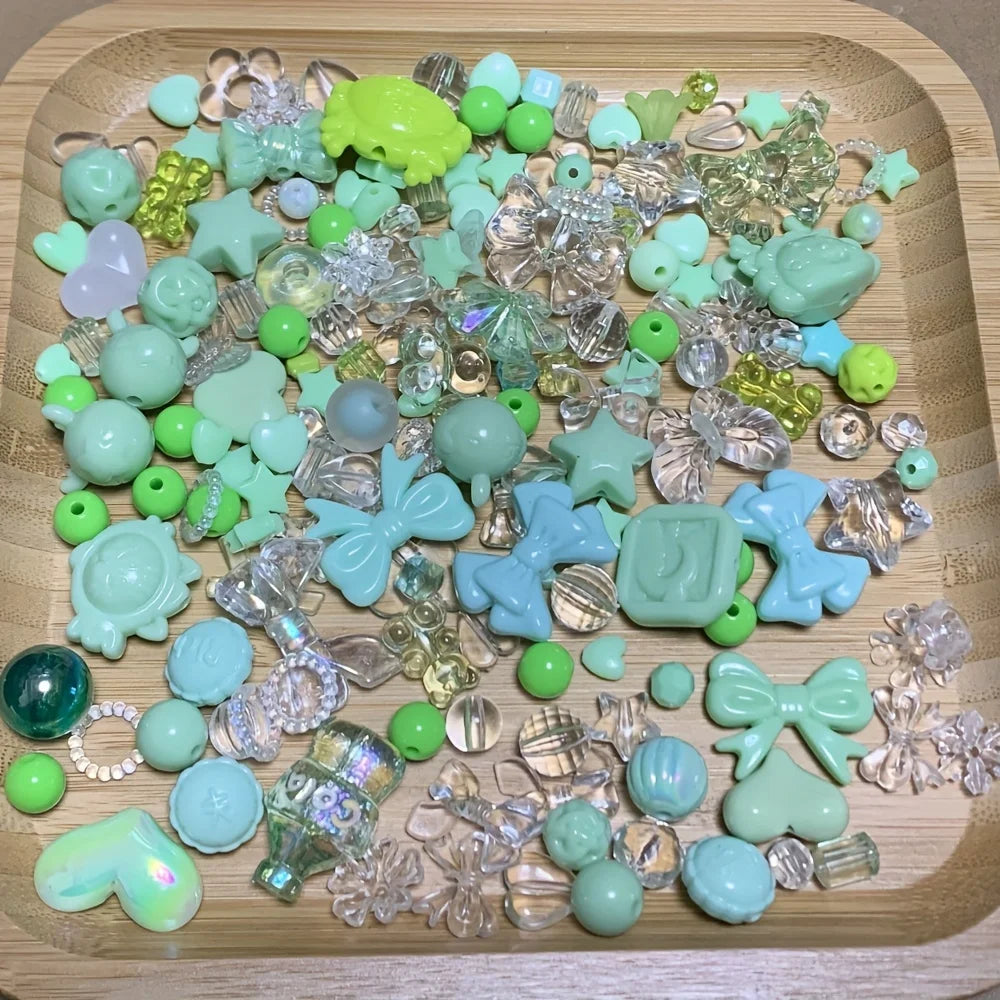 A collection of mixed green and clear acrylic loose beads for jewelry making